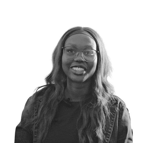Smiling young woman with glasses and long hair in a casual jacket.