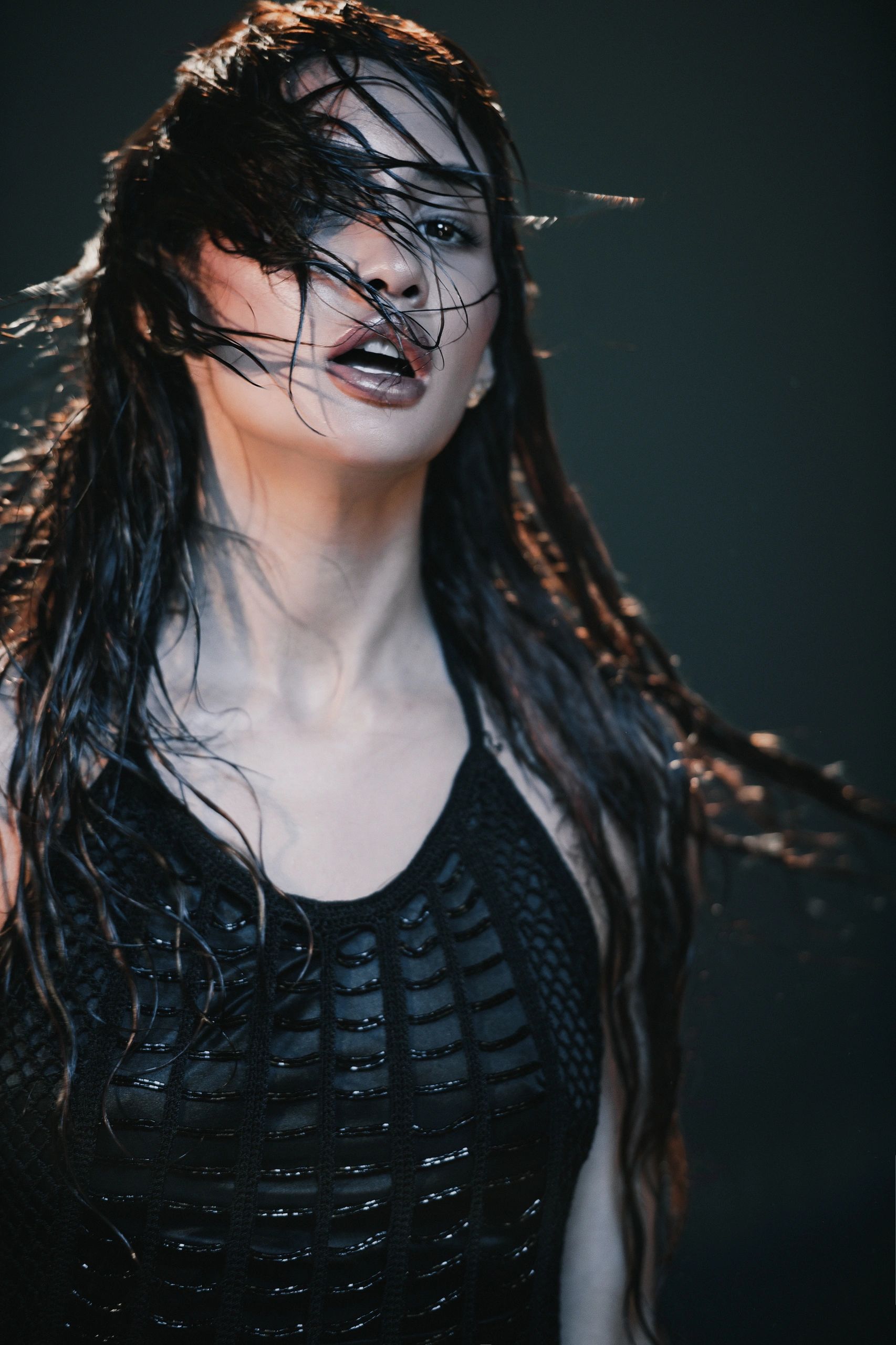 Woman with wet hair covering her face, wearing a black top.