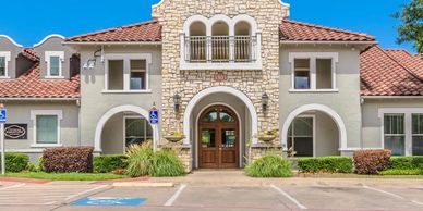 Stone and stucco building entrance with parking spaces.