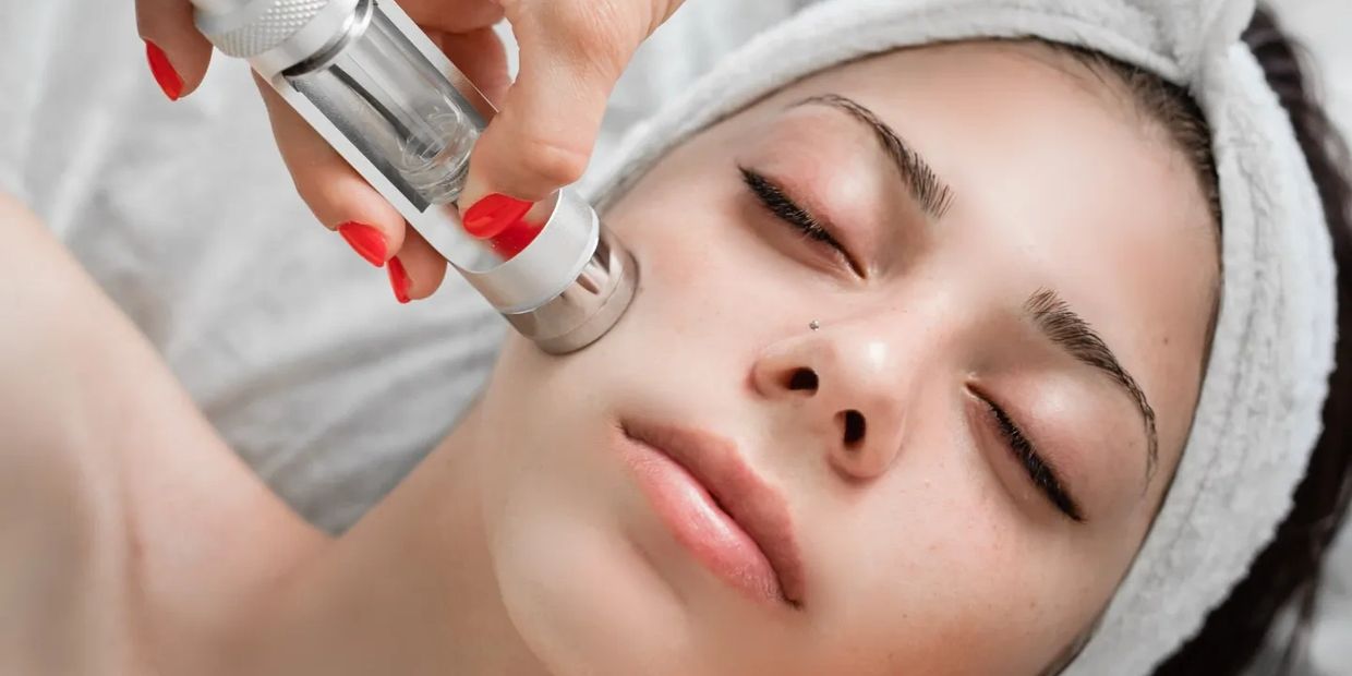 Woman receiving facial treatment with a device.