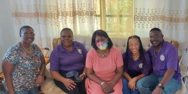 A group of five people sitting together indoors, smiling at the camera.