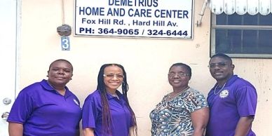 Four people standing outside a home care center, smiling at the camera.