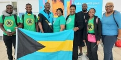 Group of people holding the Bahamas flag indoors.