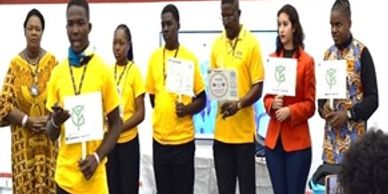 Group of people holding certificates, some wearing yellow shirts, standing in a row indoors.