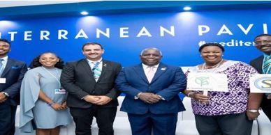 Group of six diverse professionals posing in front of a Mediterranean Pavilion sign.