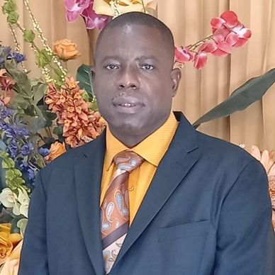 Man in formal attire posing with floral background.
