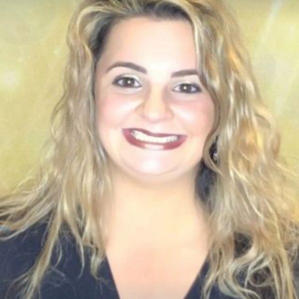 Smiling woman with curly blonde hair and dark lipstick.