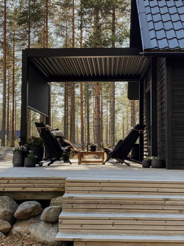 Cozy outdoor seating area on a wooden deck surrounded by pine trees.