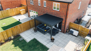 A modern backyard patio with a pergola and outdoor furniture.