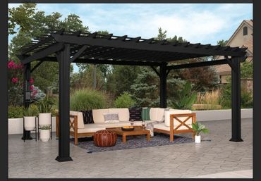 Modern black pergola shading an outdoor lounge with beige sofas and plants.