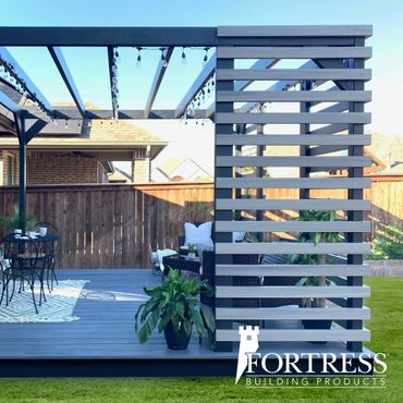 Modern backyard patio with pergola and privacy screen by Fortress Building Products.