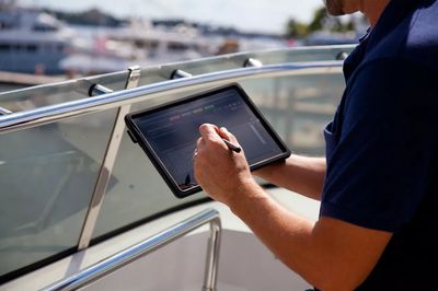 Person using a tablet with a stylus on a boat.