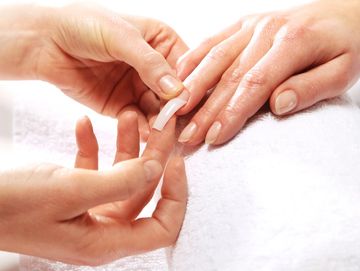 Applying a fake nail to a person's hand.