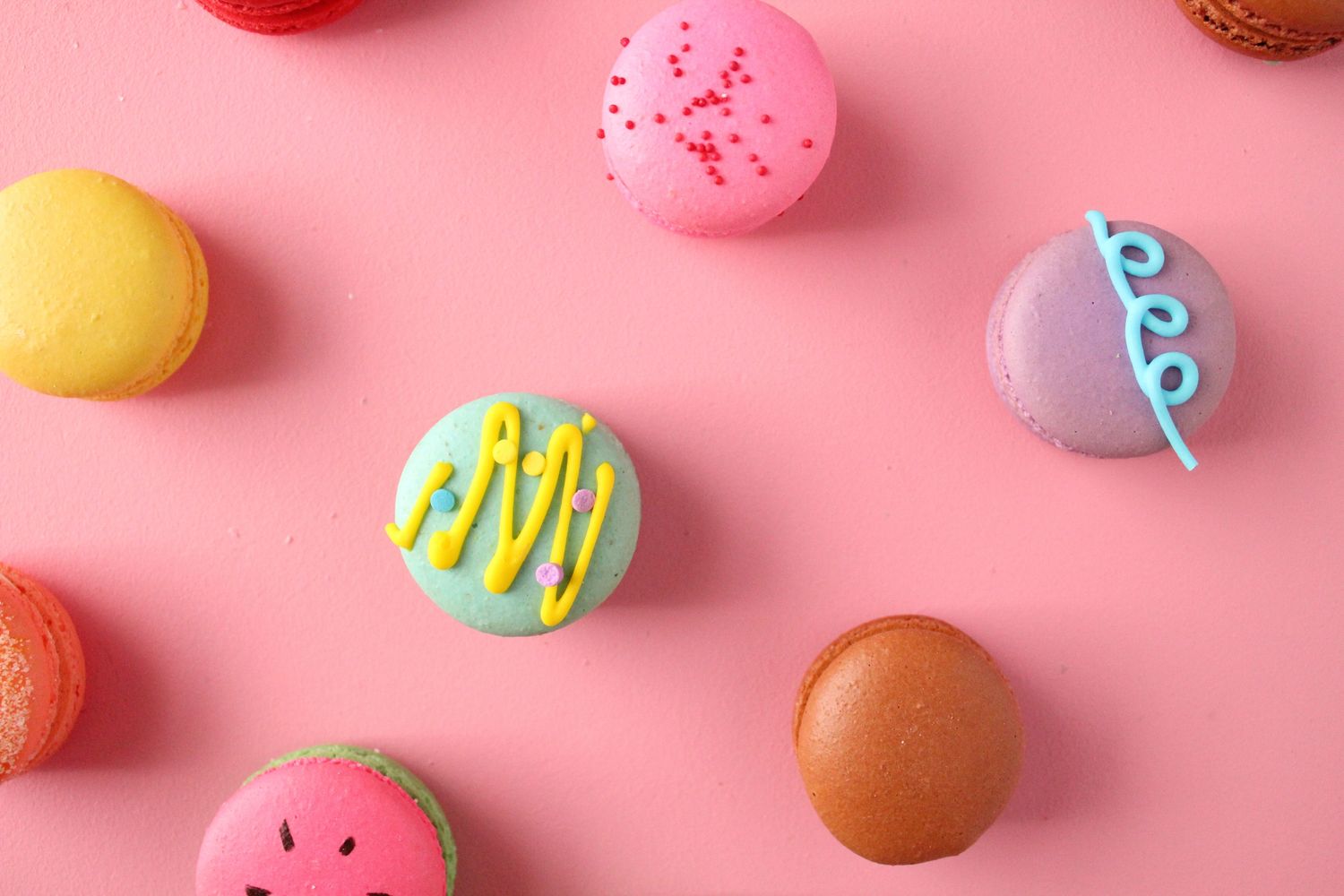 Colorful macarons on a pink background.