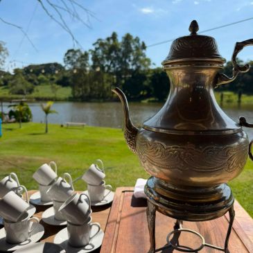 Café ao ar livre com bule vintage e xícaras.