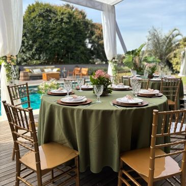 Mesa posta com toalha verde e decoração elegante ao ar livre.