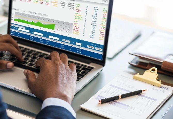 Person analyzing financial data on a laptop with documents and pen on the desk.