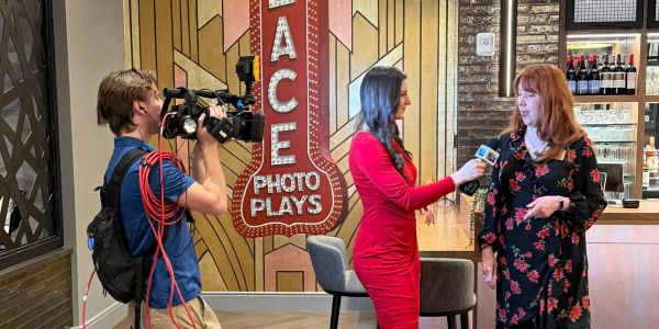 A woman interviews another while a cameraman records.