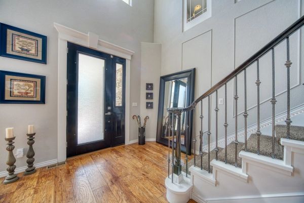 Bright entryway with wooden flooring and a black front door.