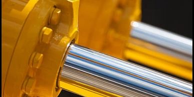 Close-up of shiny metal rods connected to a yellow mechanical part.