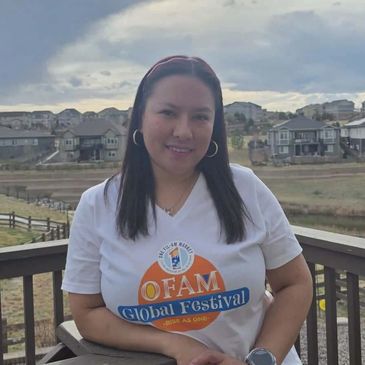 Woman smiling outdoors wearing a festival T-shirt on a balcony.