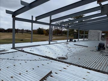 Steel framework and metal decking of a building under construction on a cloudy day.