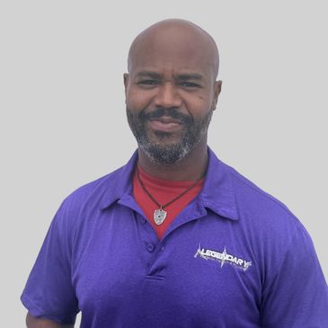 Man in purple polo shirt smiling against plain background.