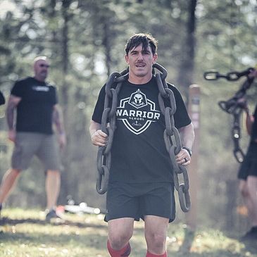 Man carrying heavy chains during outdoor fitness training.