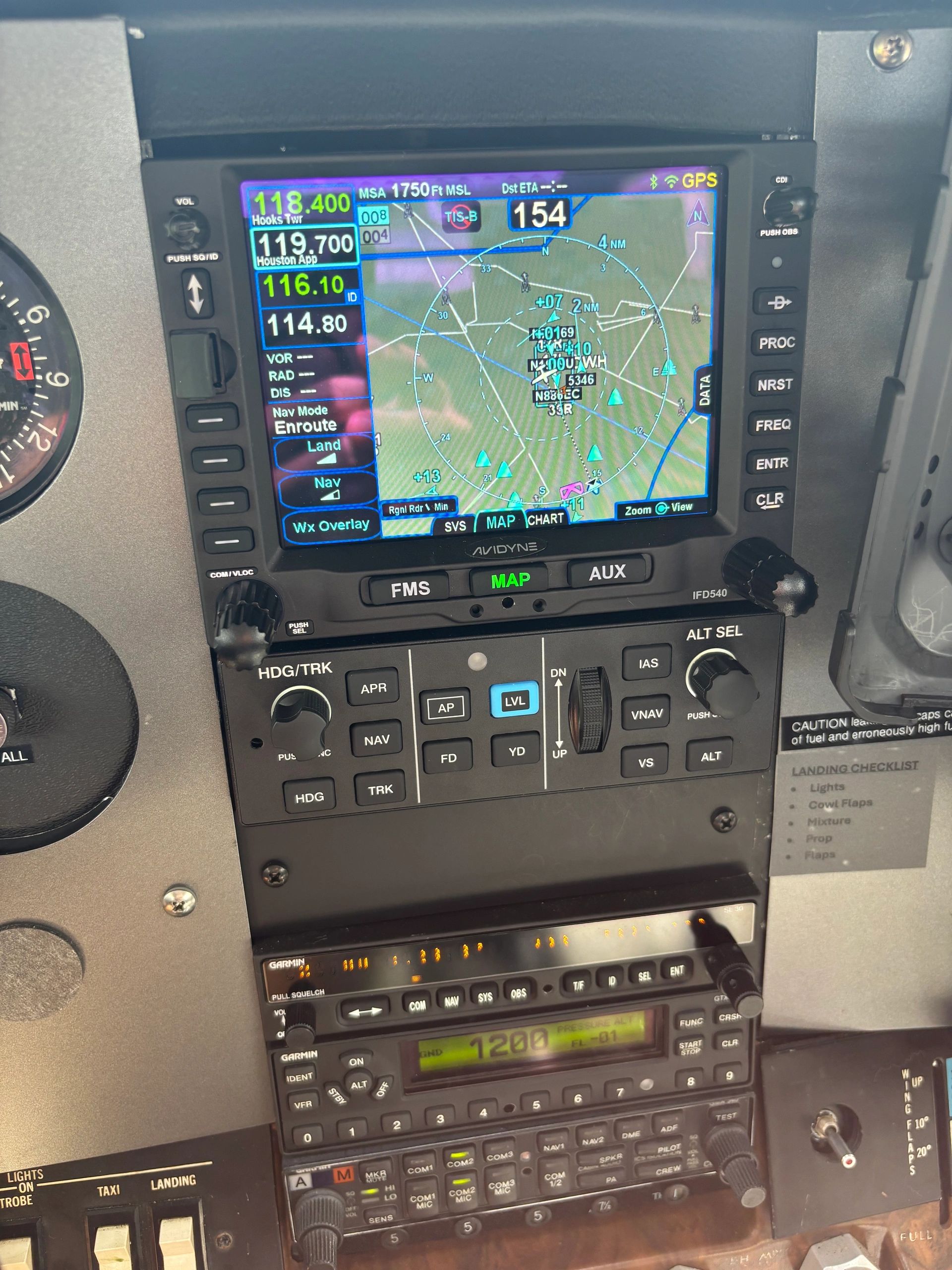 Aircraft avionics display showing navigation map and radio frequencies.