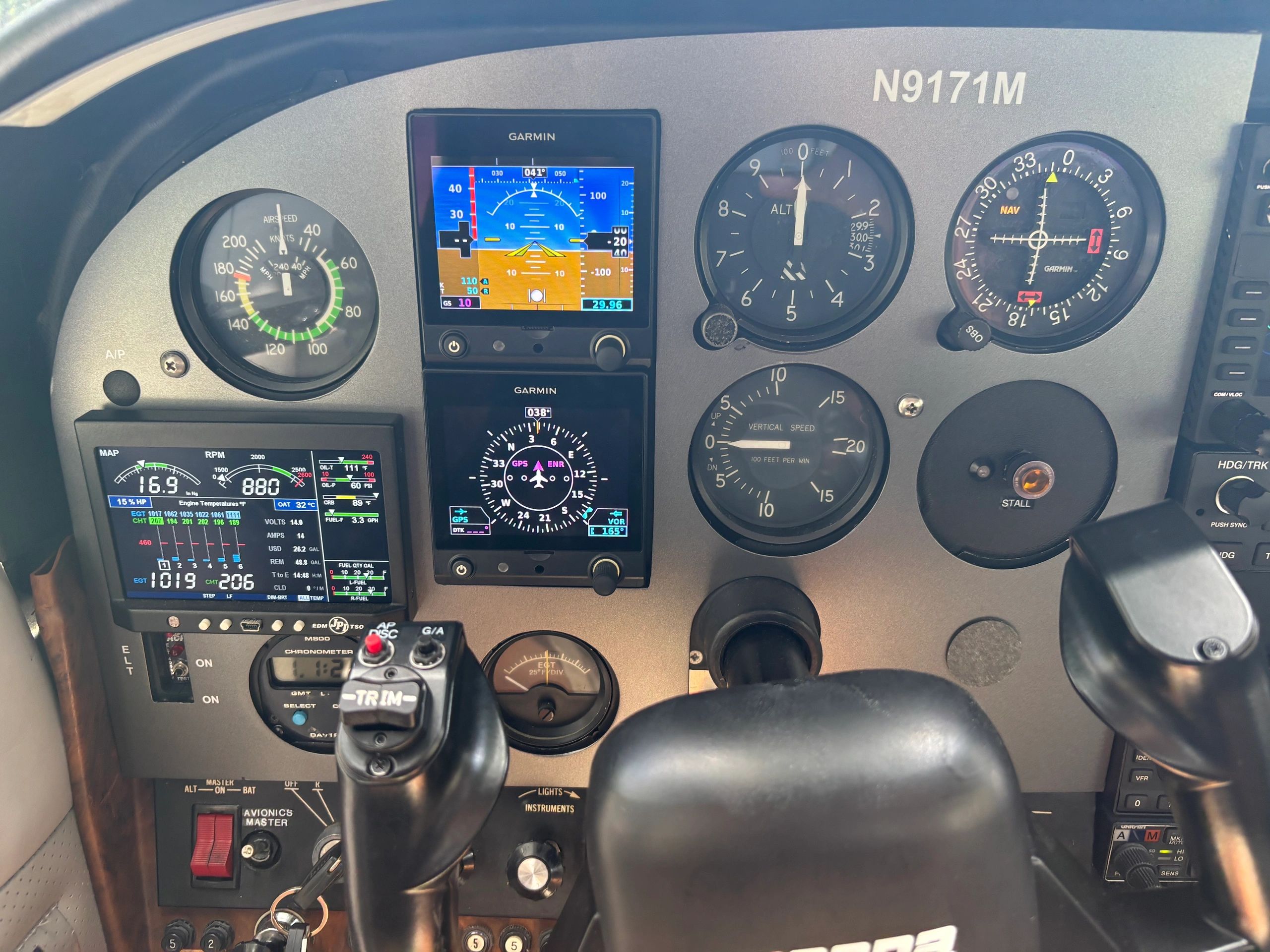 Cockpit instrument panel of a small aircraft with Garmin displays and various gauges.