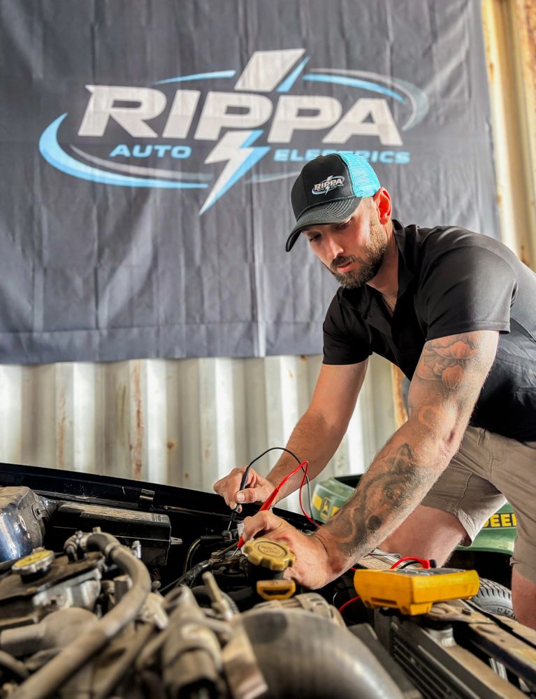 Man working on a car engine with electrical testing tools at Rippa Auto Electrics.