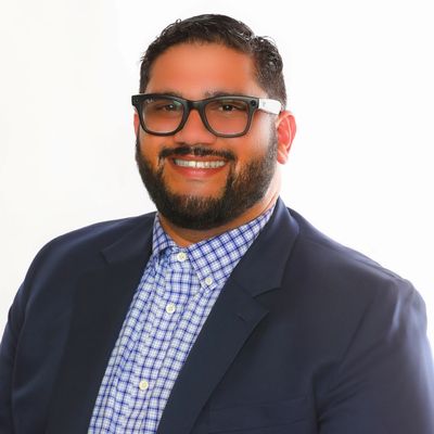 Smiling man in glasses and blazer.
