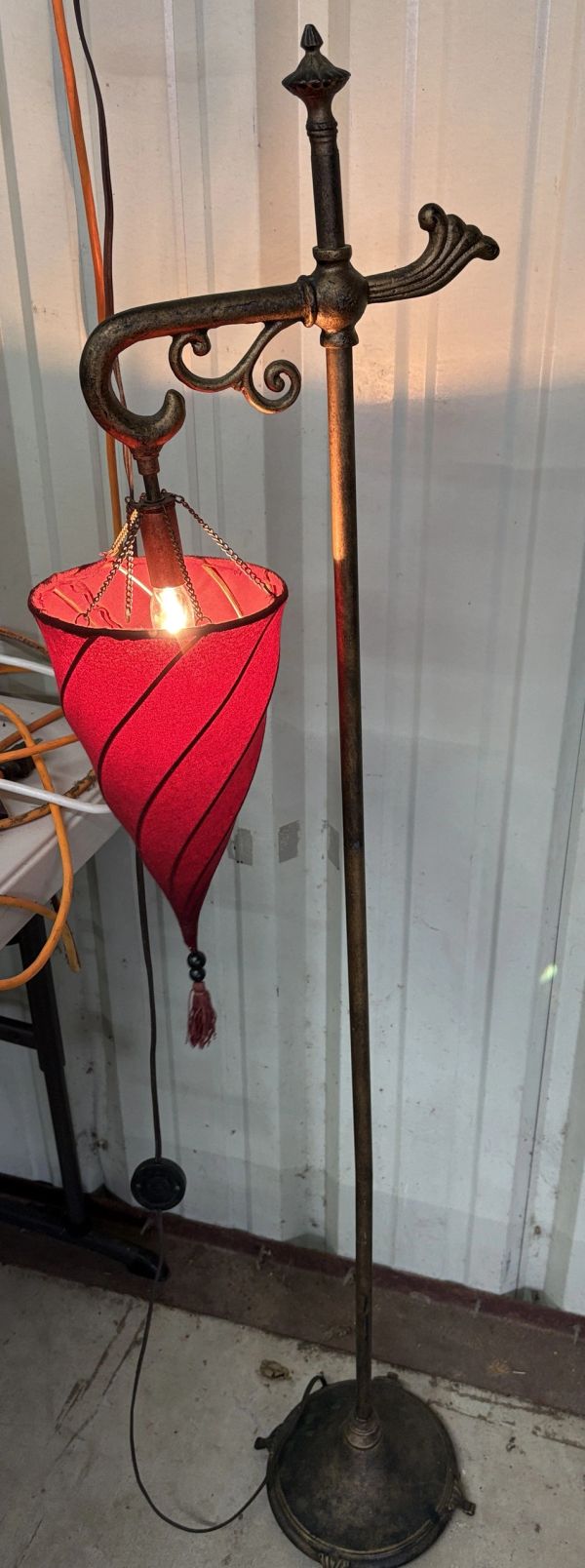 Vintage floor lamp with a red spiral fabric shade and ornate metal stand.