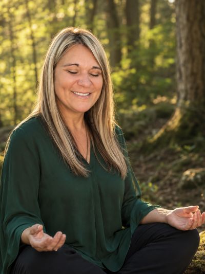 Woman meditating outdoors with a smile.