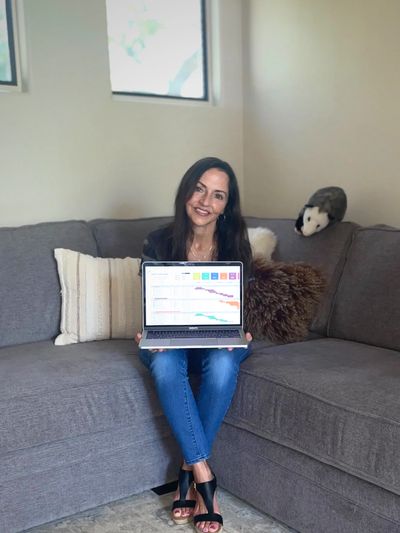 Woman sitting on a couch showing a laptop with colorful charts.