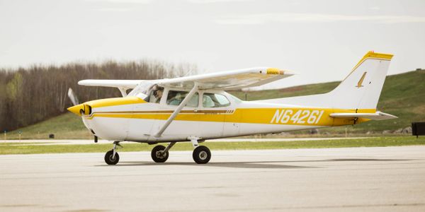 Small single-engine airplane on runway with yellow and white paint.