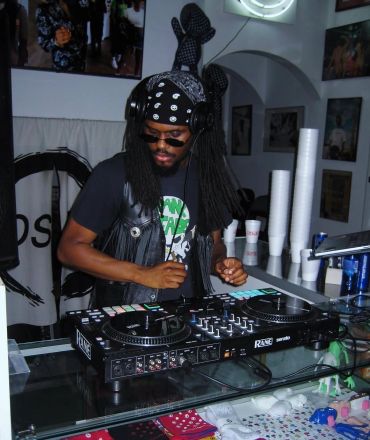 DJ playing music in a studio with headphones and sunglasses.