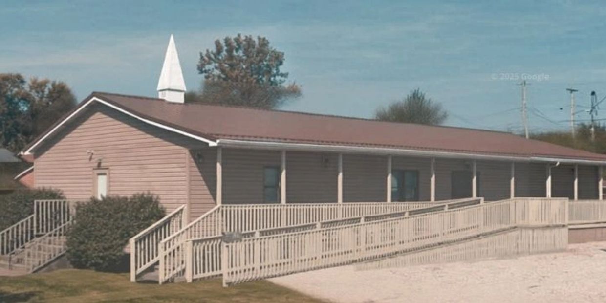 A small, single-story church with a white steeple and wheelchair ramp.