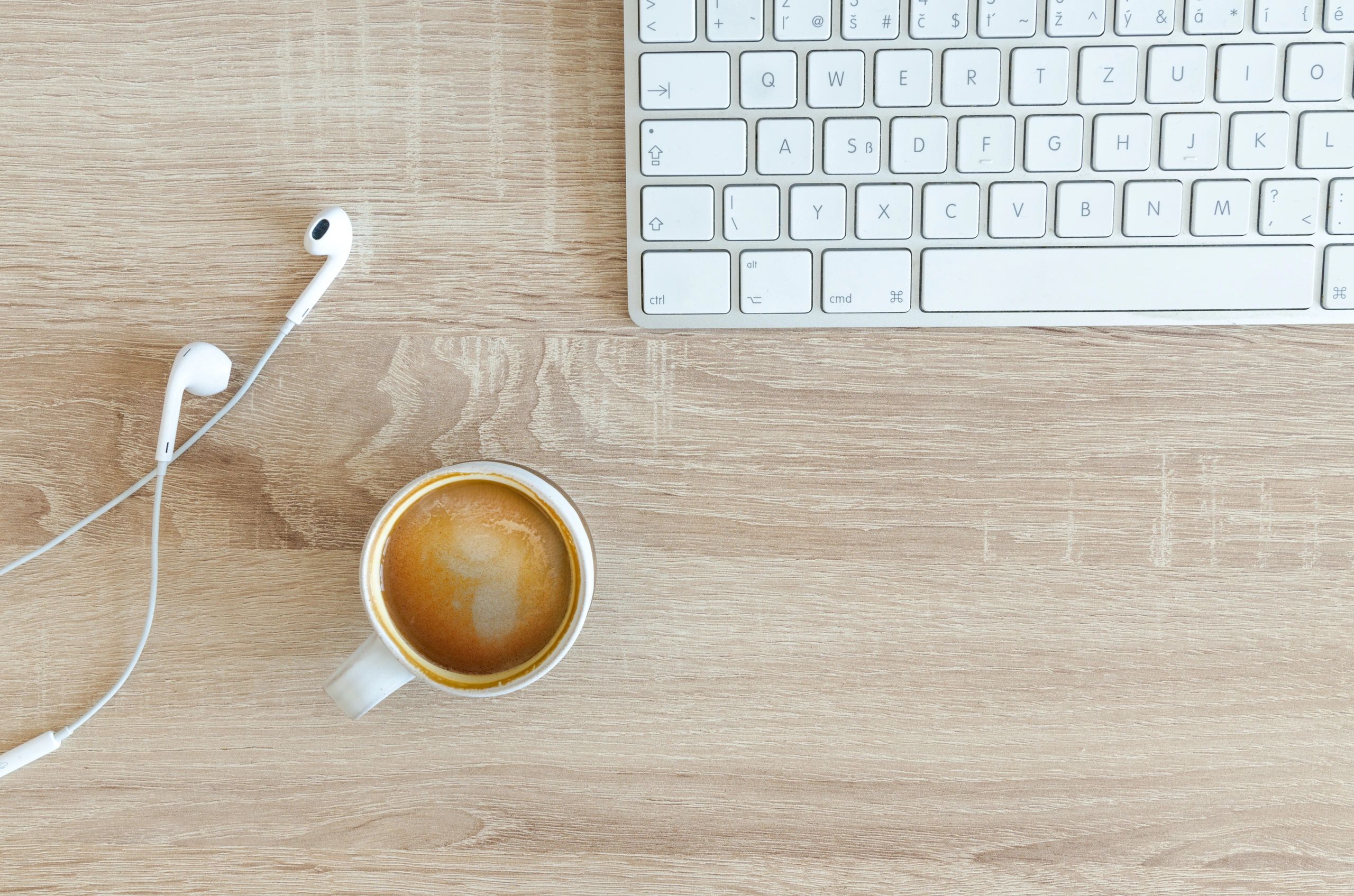 A black coffee, headphones and a key board. 