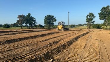 A tractor plowing a field under a clear blue sky.