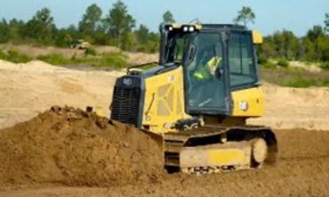 Yellow bulldozer pushing soil on a construction site.
