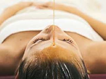 Honey being poured on a woman's forehead for skincare.
