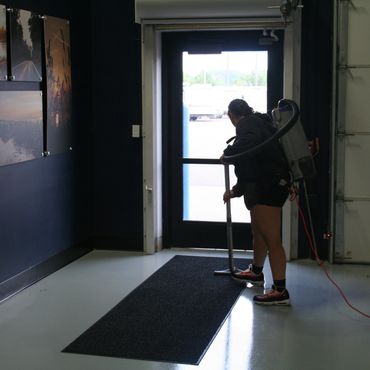 Rice Lake retail store entryway being vacuumed by cleaning technician