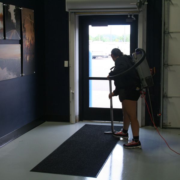 Rice Lake retail store entryway being vacuumed by cleaning technician