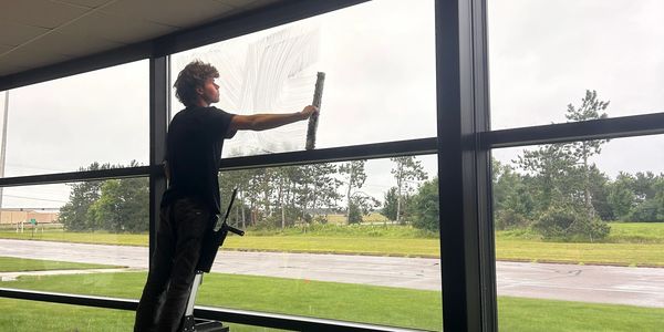 j & f facility services team member performing window cleaning services in chippewa falls