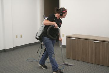 cleaning technician vacuuming a conference room at an automotive dealership in menomonie wi