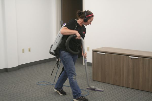 cleaning technician vacuuming a conference room at an automotive dealership in menomonie wi