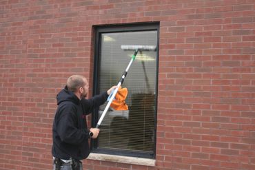 Cleaning technician washing windows at CVTC Chippewa Falls before school year