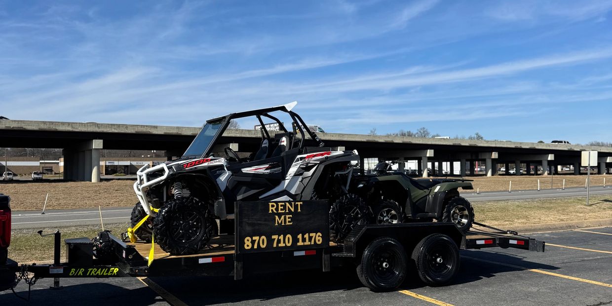 Off-road vehicles on a trailer for rent with contact number.