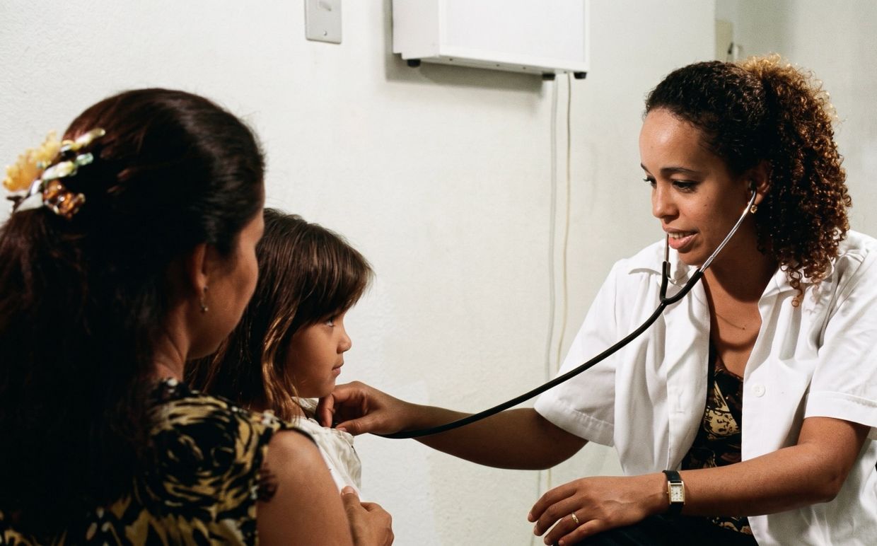 Doctor using stethoscope to check a child's heartbeat during a medical visit.